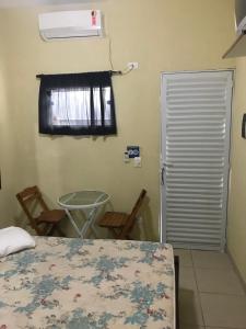 Schlafzimmer mit einem Bett, einem Fenster und einer Tür in der Unterkunft Suites em Maresias in Maresias