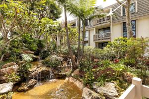 a garden with a waterfall in front of a building at Penthouse Condo w/ Panoramic Ocean Views at Beach Resort in Oceanside