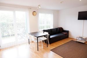 a living room with a black leather couch and a table at Outletcity Apartment Ferienwohnung Metzingen in Metzingen