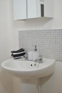 lavabo blanco en el baño con espejo en Epicsa - 3 Bedroom Family & Corporate Stay, Garden and FREE parking, en Cambridge
