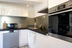 une cuisine avec des armoires blanches et un micro-ondes dans l'établissement Les Gîtes de Laure - L'Or Vert, Appartement avec Vue sur le Château, Parking Privé, Climatisation, Netflix, à 160 m de la Cité Médiévale, à Carcassonne