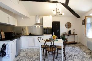 une cuisine avec des armoires blanches et une table et des chaises dans l'établissement Les Gîtes de Laure - L'Or Vert, Appartement avec Vue sur le Château, Parking Privé, Climatisation, Netflix, à 160 m de la Cité Médiévale, à Carcassonne