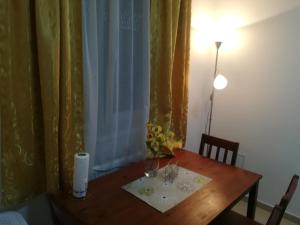a wooden table with a vase of flowers on it at Juniperus Apartman in Tiszaújváros +1 photo