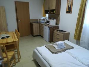 a kitchen with a bed and a table and a microwave at Juniperus Apartman in Tiszaújváros