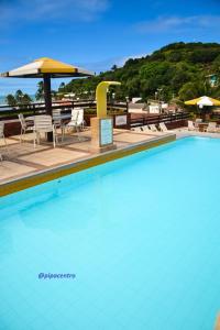 uma piscina com cadeiras e mesas e um guarda-sol em Flat Pipa Oceano em Pipa