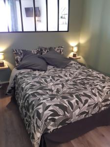 a bed with a black and white comforter and two lamps at COSYLOC studios in Cergy