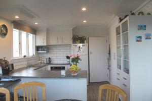 a kitchen with white cabinets and a white refrigerator at Rosies Place in Oamaru