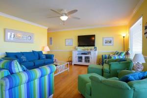 uma sala de estar com sofás azuis e uma televisão de ecrã plano em Summer Sandcastle em Holden Beach