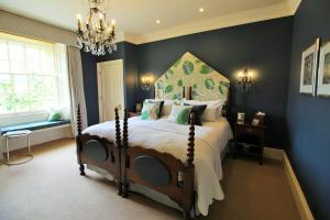 a bedroom with a bed with blue walls and a chandelier at The Swan Hotel in Bibury