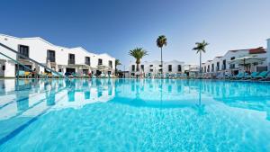 una piscina en un complejo con palmeras y edificios en FBC Fortuny Resort - Adults Only, en Maspalomas