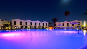 a large swimming pool at night with purple lights at FBC Fortuny Resort - Adults Only in Maspalomas