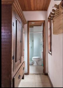 a bathroom with a toilet and a wooden cabinet at Pousada Palavras Novas in Lavras Novas
