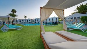 a resort with two beds and umbrellas and a pool at FBC Fortuny Resort - Adults Only in Maspalomas