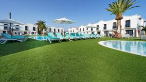 a row of blue lounge chairs next to a swimming pool at FBC Fortuny Resort - Adults Only in Maspalomas