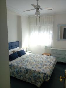 1 dormitorio con 1 cama con edredón azul y ventana en By The Sea, en Nerja