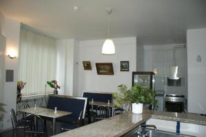 a dining room with tables and chairs and a kitchen at Hotel Garni Aaberna in Berlin