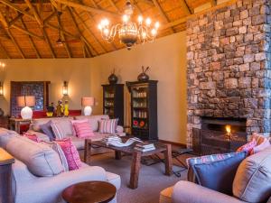 uma sala de estar com sofás e uma lareira de pedra em aha Thakadu River Camp em Madikwe Game Reserve