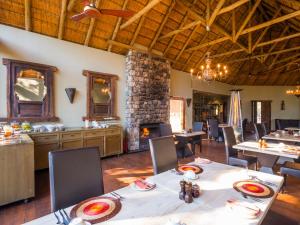 a dining room with tables and chairs and a fireplace at aha Thakadu River Camp in Madikwe Game Reserve