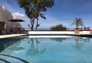 duży basen z błękitną wodą i palmami w obiekcie HOTEL CANDELERO w mieście Yuriria