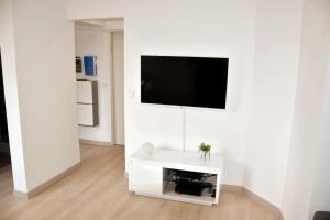 a white living room with a flat screen tv on a wall at Bel appartement situé quartier Louvre-Bollaert in Lens