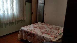 a bedroom with a bed with a flowered blanket on it at Ubatuba Tenório apto térreo 6 pess in Ubatuba