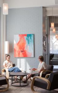 two women sitting in chairs in a room with a painting at Hotel Saint George in Marfa