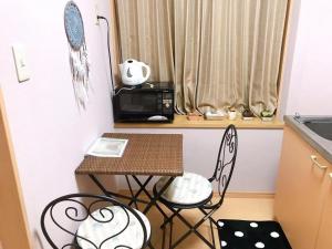 eine kleine Küche mit einem Tisch, Stühlen und einer Mikrowelle in der Unterkunft Mori de house in Kobe 201 in Kōbe