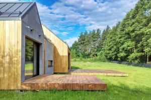 a house with a wooden deck in a field at Modern house in front of the forest in Słupsk