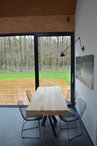 a wooden table and chairs in front of a large window at Modern house in front of the forest in Słupsk