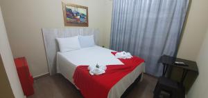 - une petite chambre avec un lit blanc et une couverture rouge dans l'établissement Pertinho do Aeroporto Hospedagem Particular, à Várzea Grande
