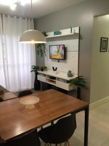 a dining room with a table and a tv on a wall at Apto 3 quartos em Araranguá in Araranguá