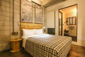 a bedroom with a bed with a checkered blanket at Hotel PaPa Whale in Taipei