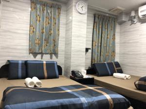 um quarto com duas camas e um relógio na parede em Dreamland Guest House em Hong Kong