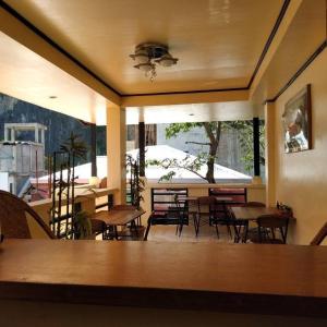 a dining room with tables and chairs and a large window at Just Inn in El Nido