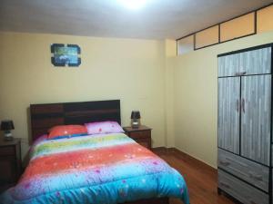 ein Schlafzimmer mit einem farbenfrohen Bett und einer Kommode in der Unterkunft Apartamento amueblado, cómodo e independiente en Huancayo in Huancayo