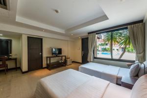a hotel room with two beds and a large window at Hotel Tropicana Pattaya in Pattaya Central