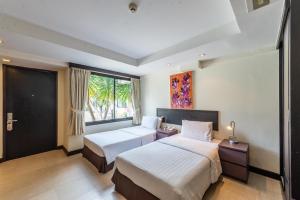 a hotel room with two beds and a window at Hotel Tropicana Pattaya - SHA Extra Plus by D N A in Pattaya
