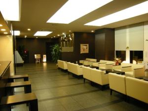 Hotel Route-inn Natori في Natori: غرفة طعام مع كراسي وطاولات بيضاء
