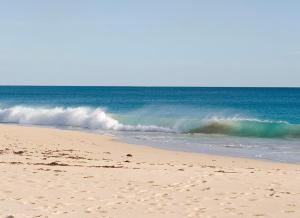 a wave in the ocean on a sandy beach at Ocean View Motel in Perth