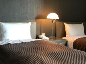 una camera d'albergo con un letto e un telefono su un tavolo di Hotel New White House a Rumoi