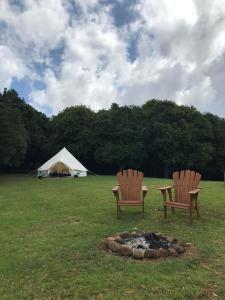two chairs and a fire pit in a field with a tent at Luxury Tee Pee Byron Bay in Minynon