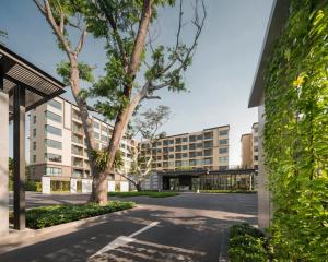 a large building with a tree in front of it at Let’s me sea@Rain Cha-am in Cha Am