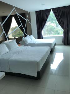 two beds in a room with two large windows at GOODY HOTEL in Johor Bahru