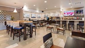 a restaurant with tables and chairs and a bar at Best Western Plus Kansas City Airport - KCI East in Kansas City