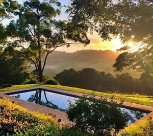 a pond in a park with the sunset in the background at Luxury Tee Pee Byron Bay in Minynon