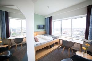 - une chambre avec un lit, un bureau et 2 fenêtres dans l'établissement Comwell Aarhus Dolce by Wyndham, à Aarhus