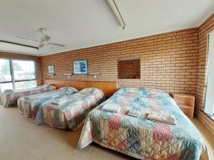 a room with three beds and a brick wall at Bayview Motor Inn in Eden