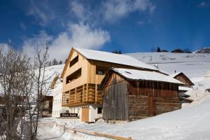 una cabaña de madera en la nieve con nieve en Ciasa Soplà, en San Cassiano