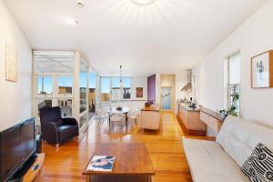 uma grande sala de estar com um sofá e uma mesa em Coastal Penthouse at Coogee Beach em Sidney