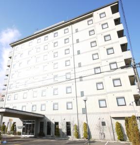 a large white building with windows at Hotel Route-Inn Kani in Kani
